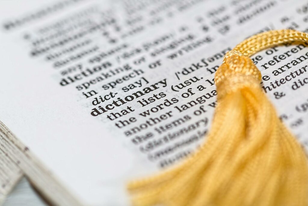 Close-up image of a dictionary page focused on the word 'dictionary' with a yellow tassel.